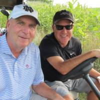 Two men in golf cart with hotdogs